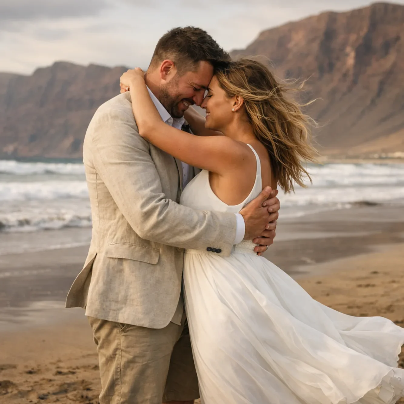 Coppia di sposi che si abbraccia sulla spiaggia di Famara a Lanzarote con oceano e scogliera sullo sfondo